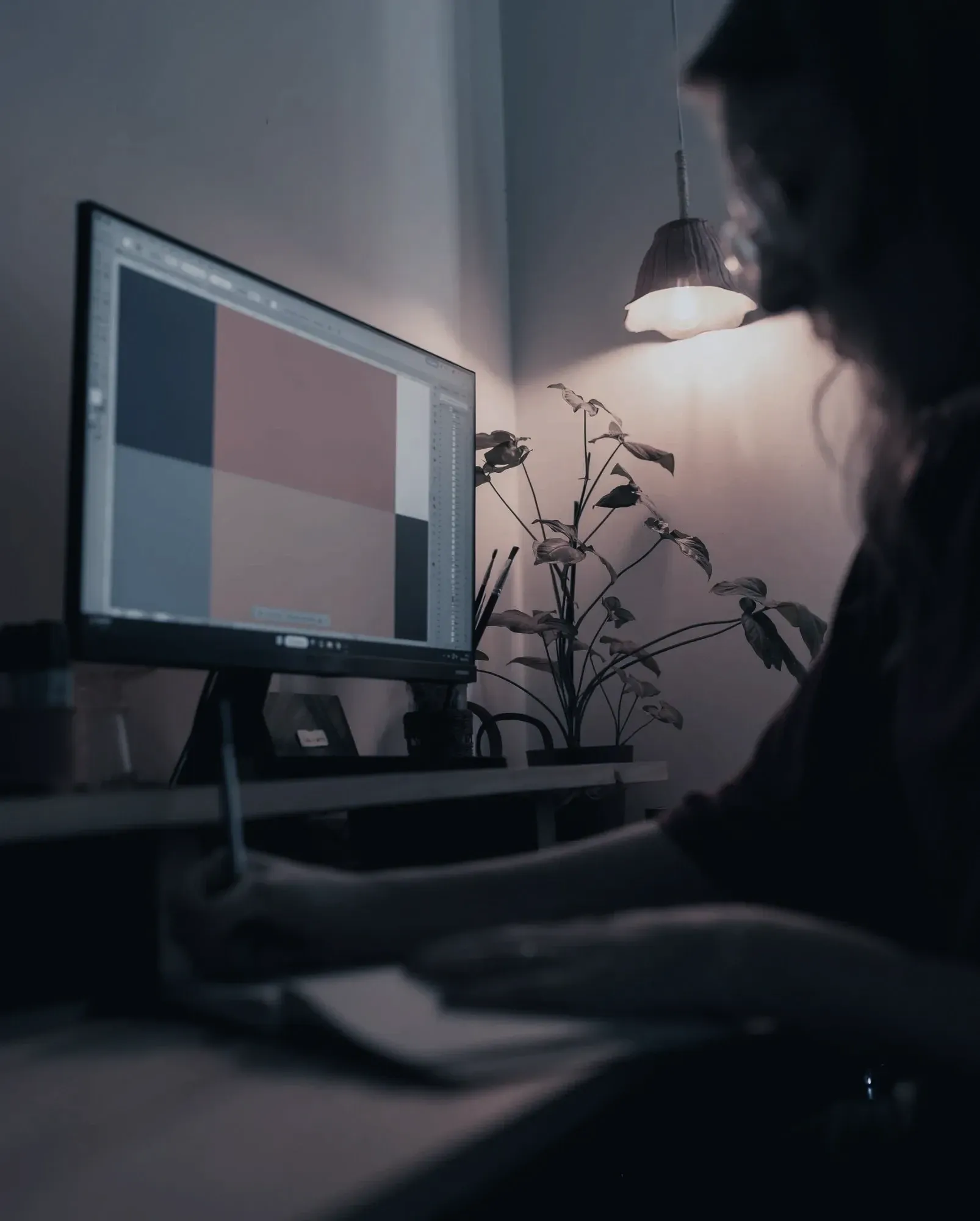 A designer sketching a page layout at a desk by lamplight
