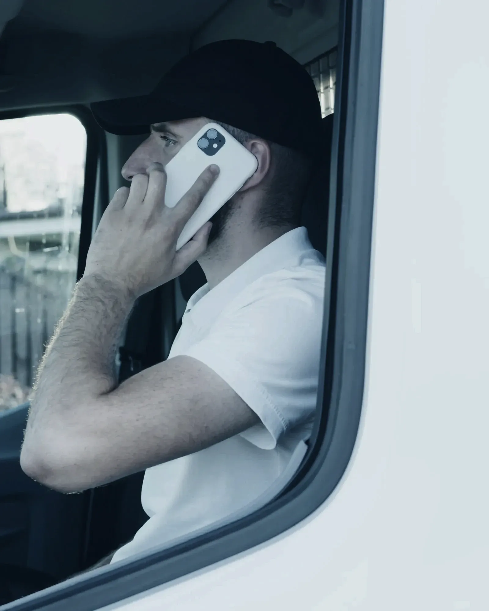 A tradesperson taking a phone call from the driver's seat of a van